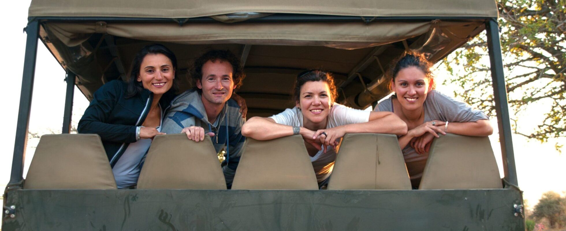 Safari jeep with four people looking out at the back