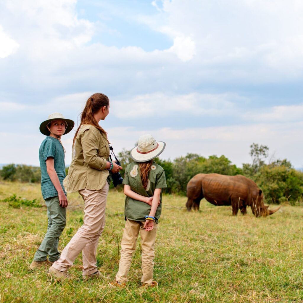 Woman and two kids looking at rhinos during a safari