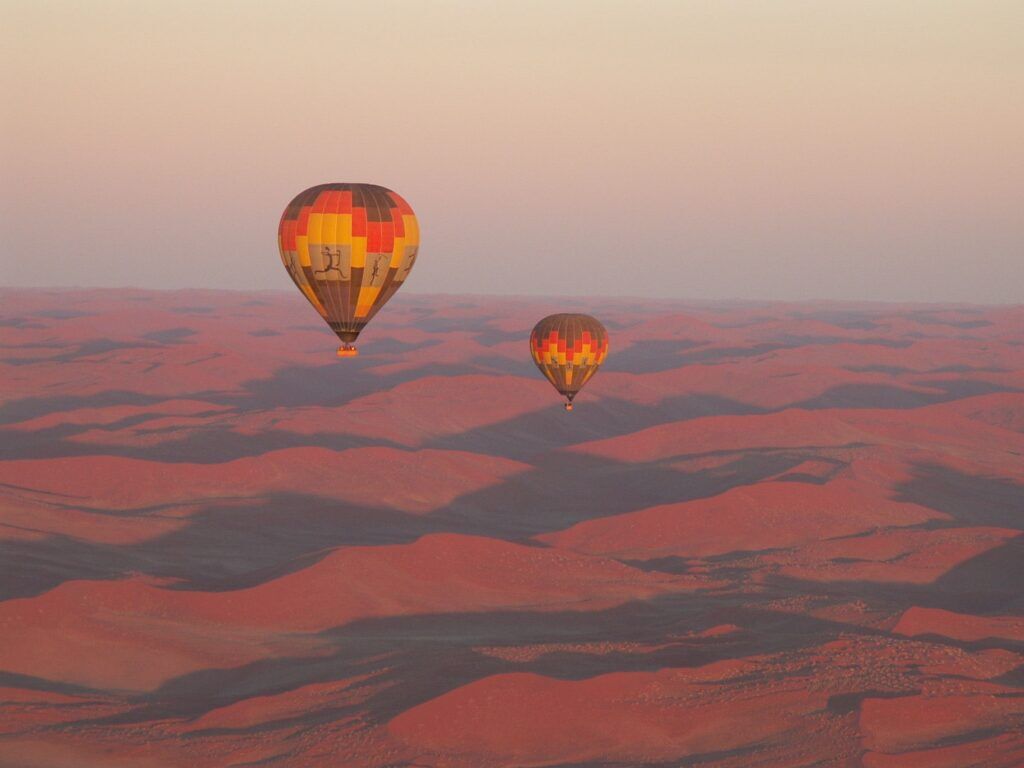 Two hot air balloons during sunrise above the Namib desert
