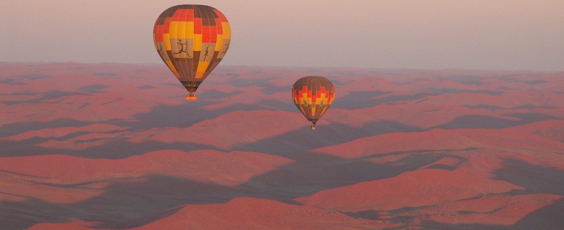 Two hot air balloons during sunrise above the Namib desert