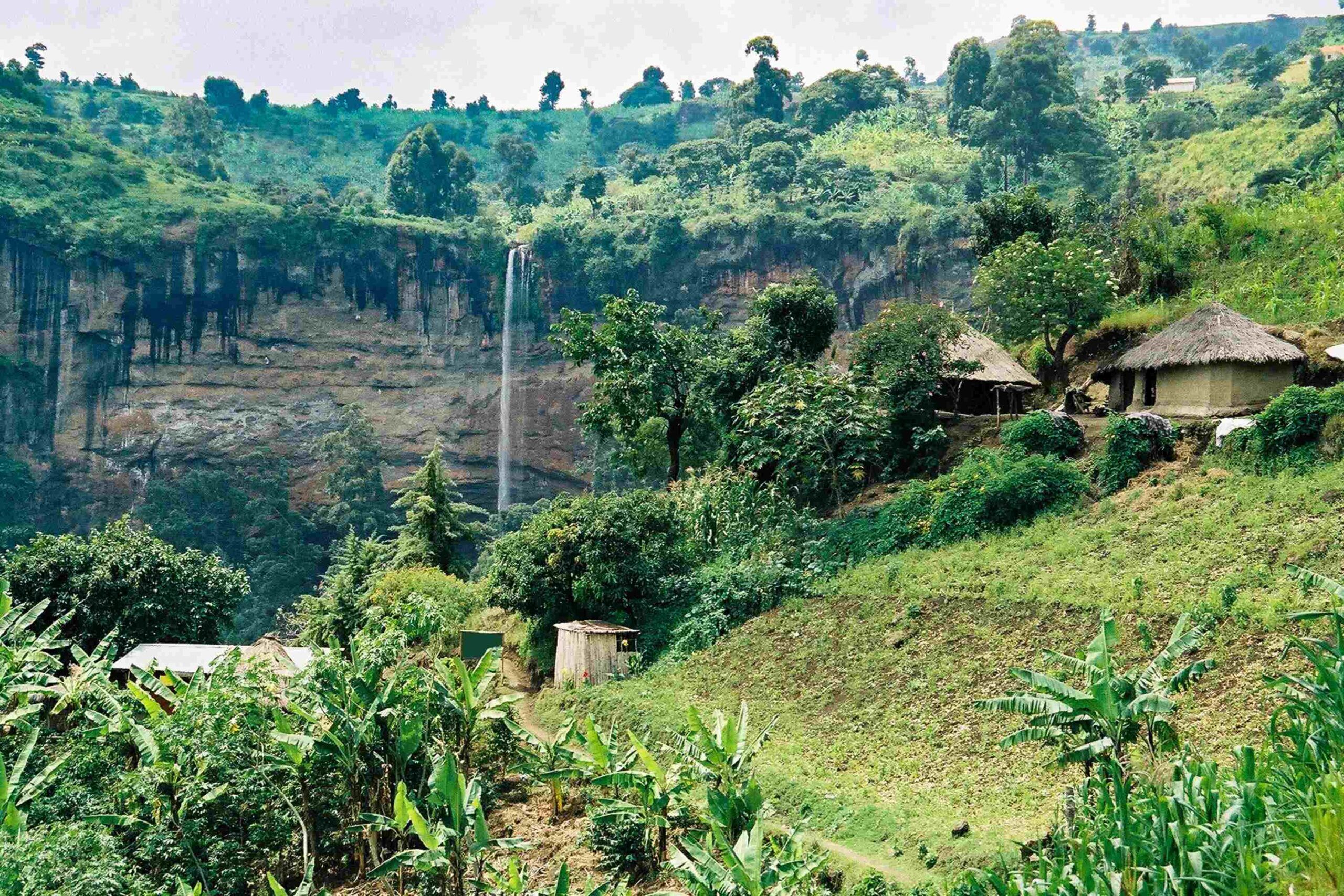 Houses on green hills with Sipi Falls waterfall in the background