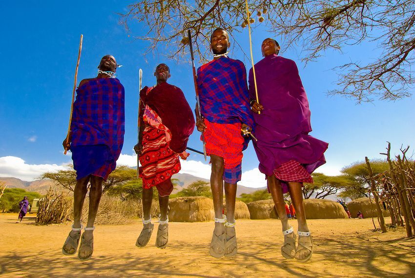 Maasai community members performing a traditional jumping dance in a village.